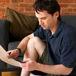 young man sitting on couch looking at paperwork