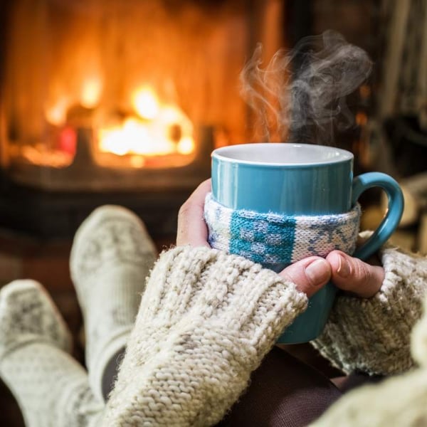 woman drinking from mug in front of fireplace