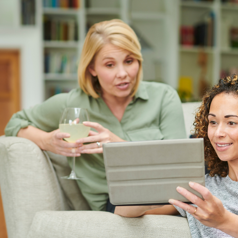 two women sitting on couch with ipad deciding to buy or lease a car
