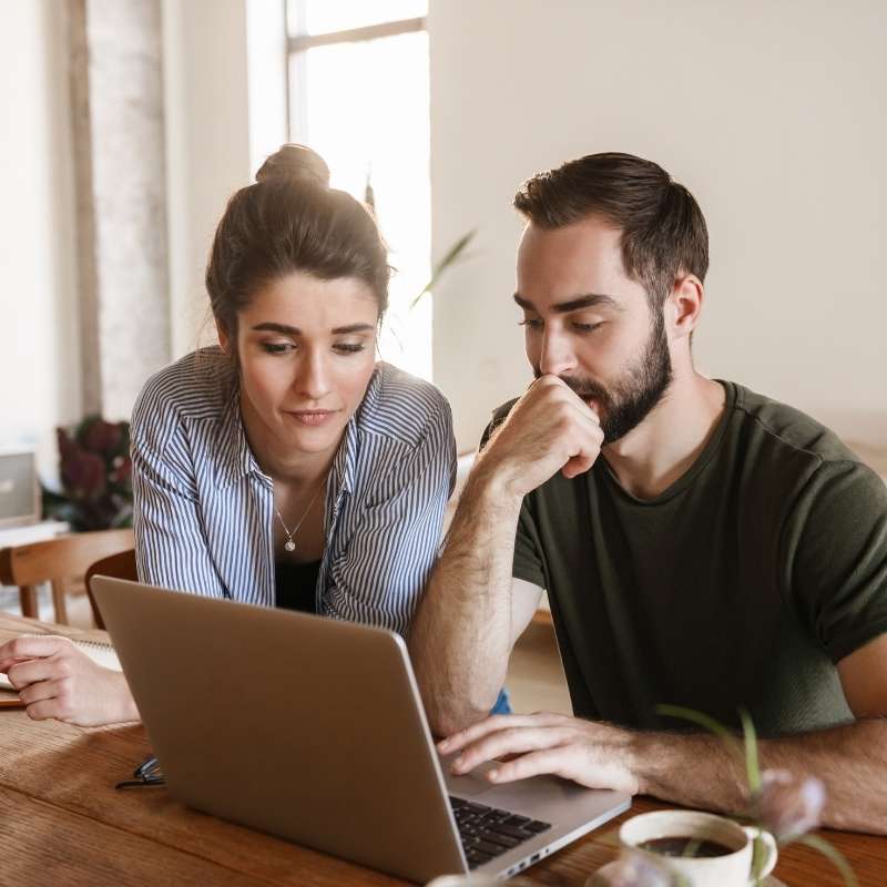 man and woman at kitchen counter looking at laptop screen
