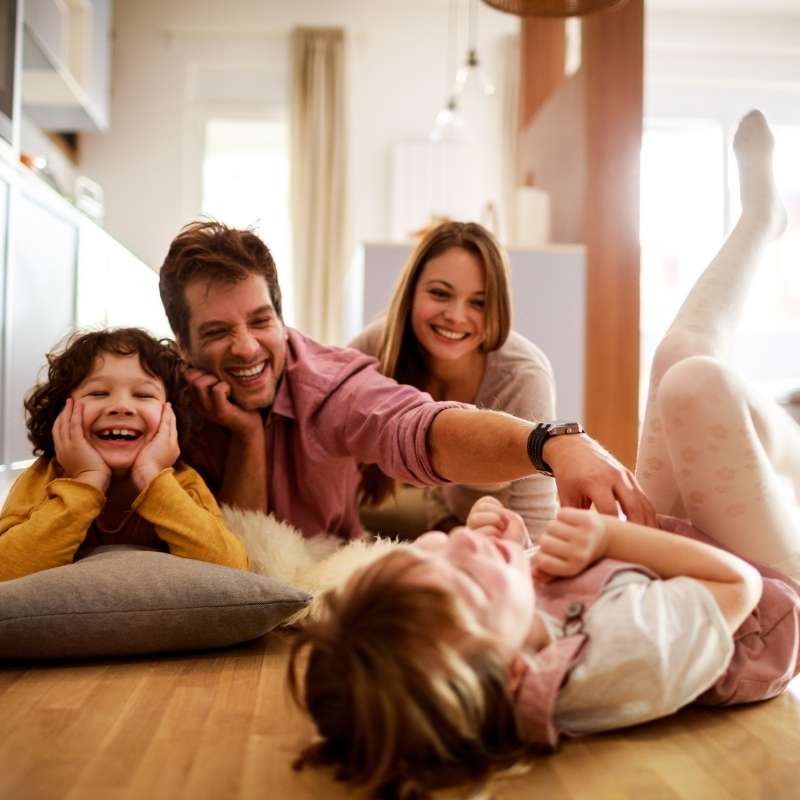 family of four on living room floor laughing