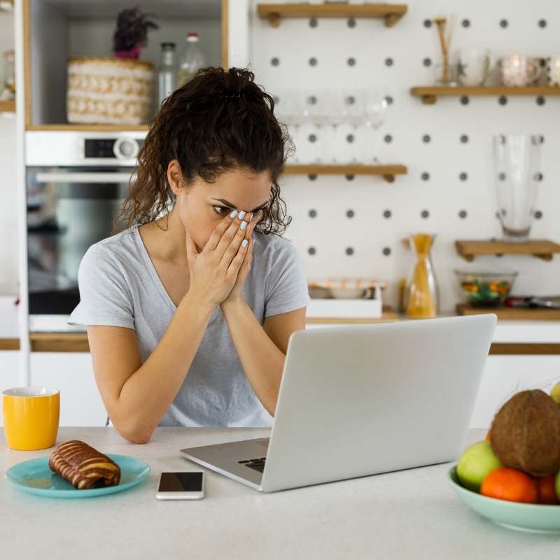 woman at laptop with hands over her mouth looking shocked