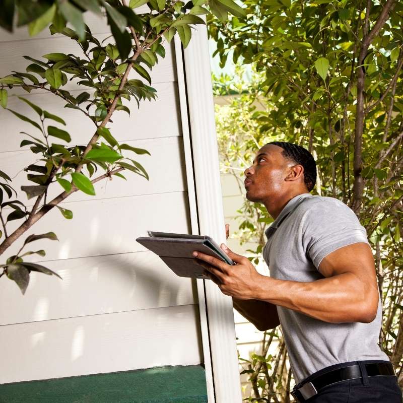 Black man holding portfolio outside a home as he inspects it for energy savings