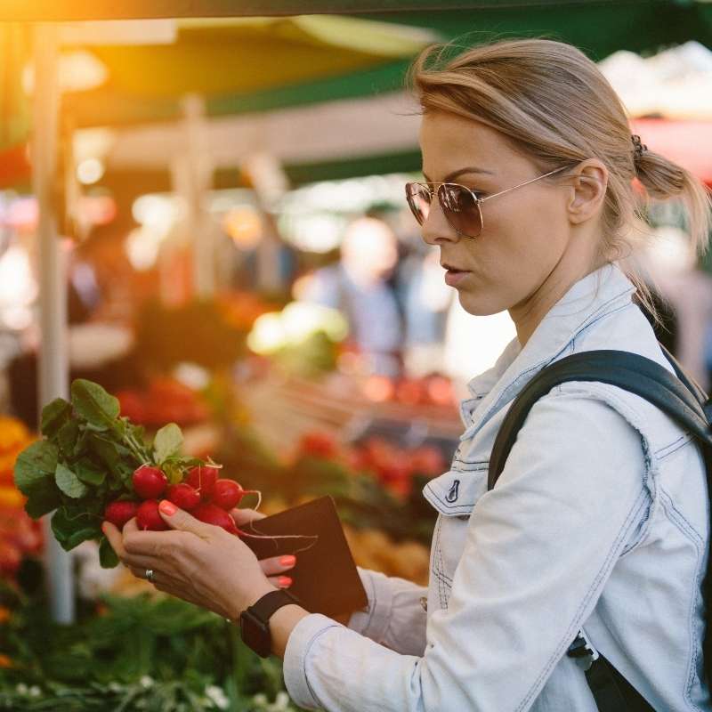 woman at outdoor market holding radishes