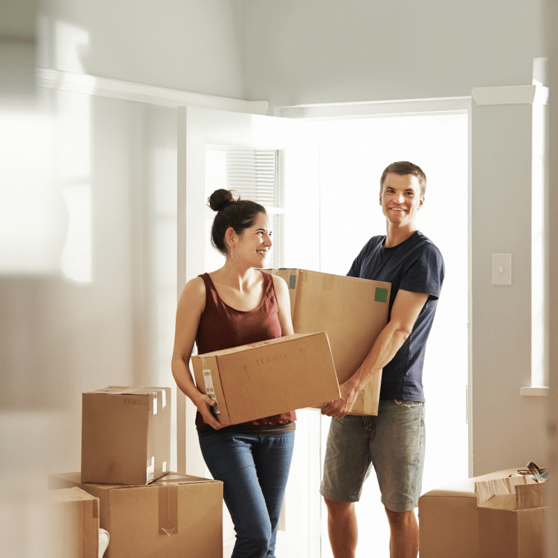 young man and woman coming in to new home with carrying moving boxes