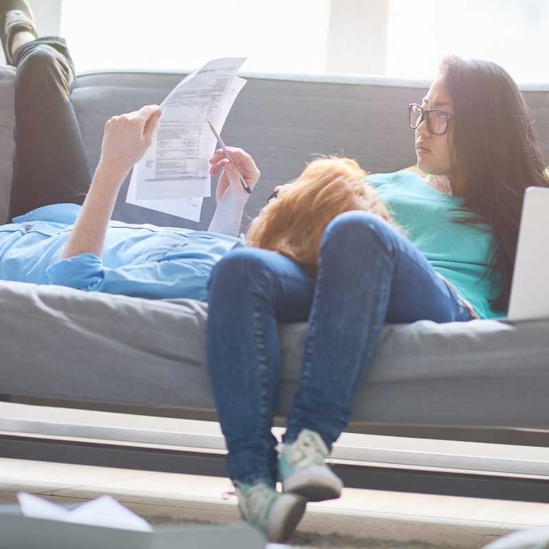 young couple on couch filling out tax forms