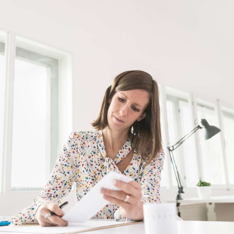 woman looking at check and checking account on laptop
