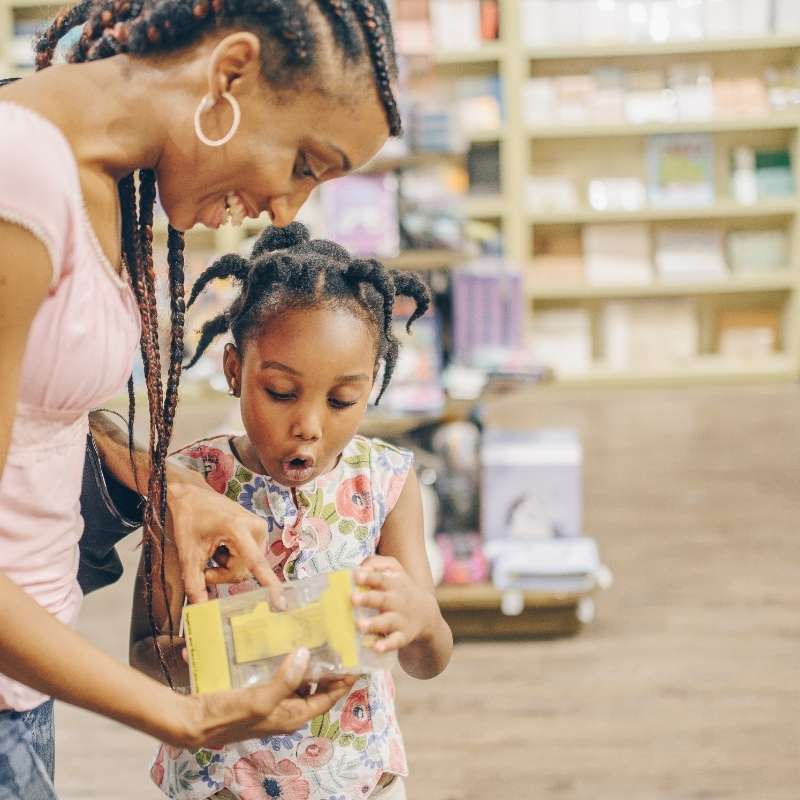 mom and daughter looking at toy in toy shop
