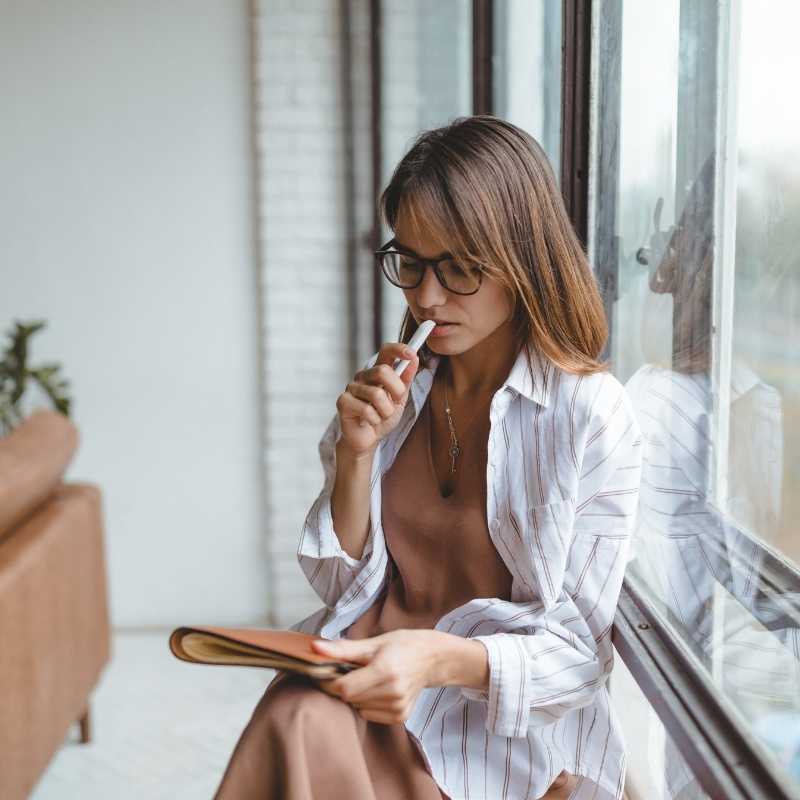 woman sitting near window looking thoughtful