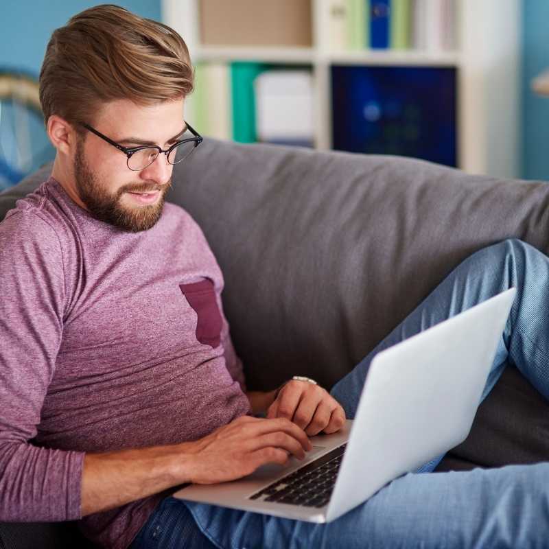 young man on couch looking at credit score on laptop