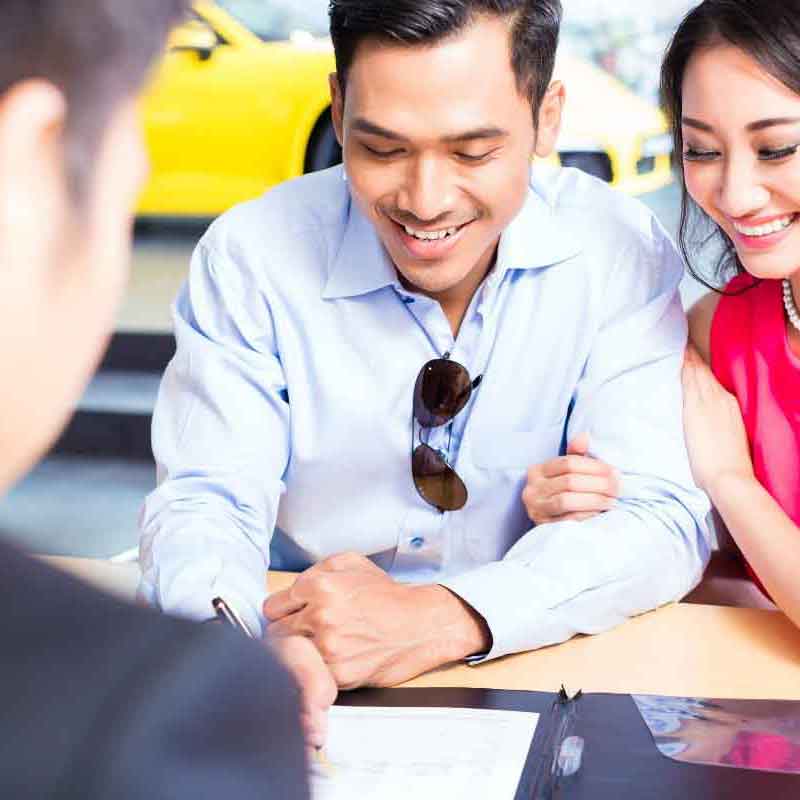 Man and woman looking at lease agreement for car