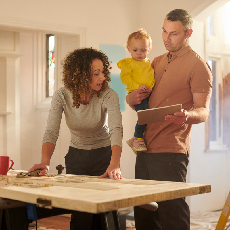 woman and man with baby in kitchen working on home renovations