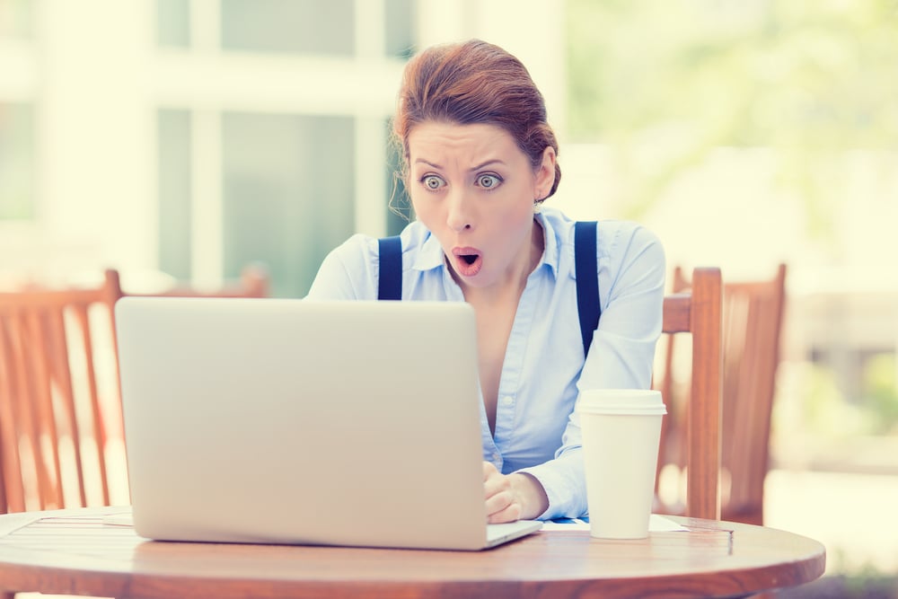 shocked young woman looking at laptop