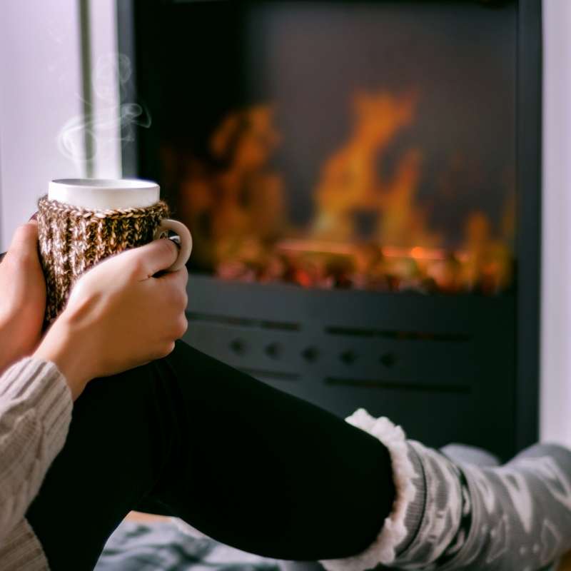 woman sitting in front of fireplace saving energy