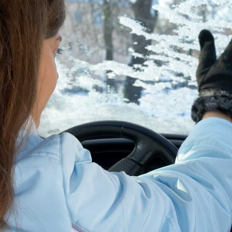 young woman driving car in winter