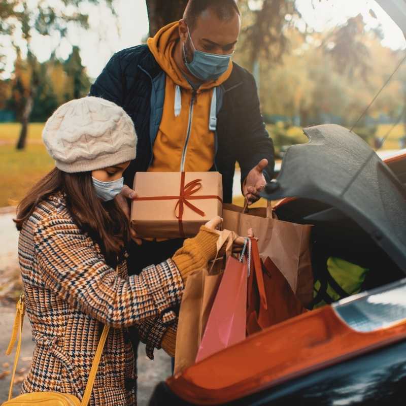 man and woman putting holiday gifts in trunk