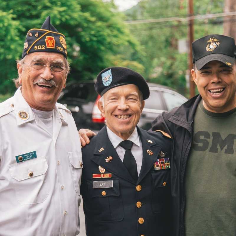 Three veterans smiling with arms around each other