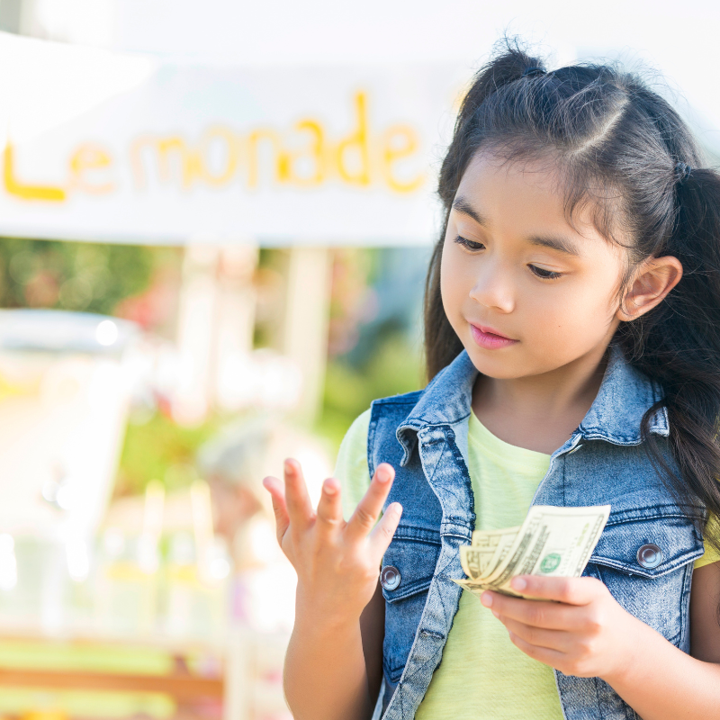 A young Asian girl counts up her earnings from her first lemonade stand. 