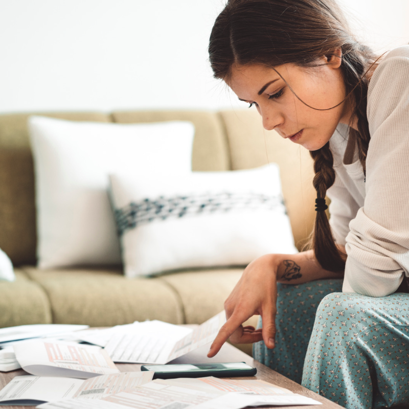 dark haired woman sitting on couch with paperwork in front of her on coffee table